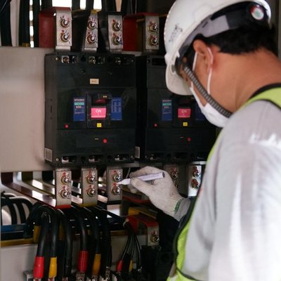 Electrician working with both hands inside a panel