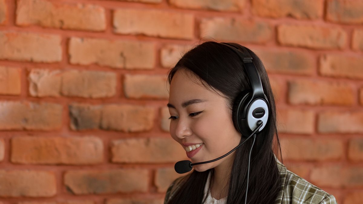 Receptionist wearing a headset, smiling while reviewing notes